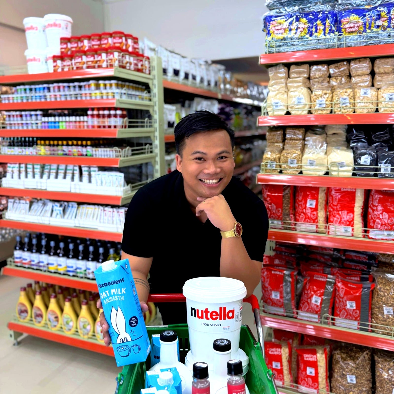 A smiling team member with a shopping cart of Oatbedient oat milk and pantry favorites in a Chefs and Bakers aisle